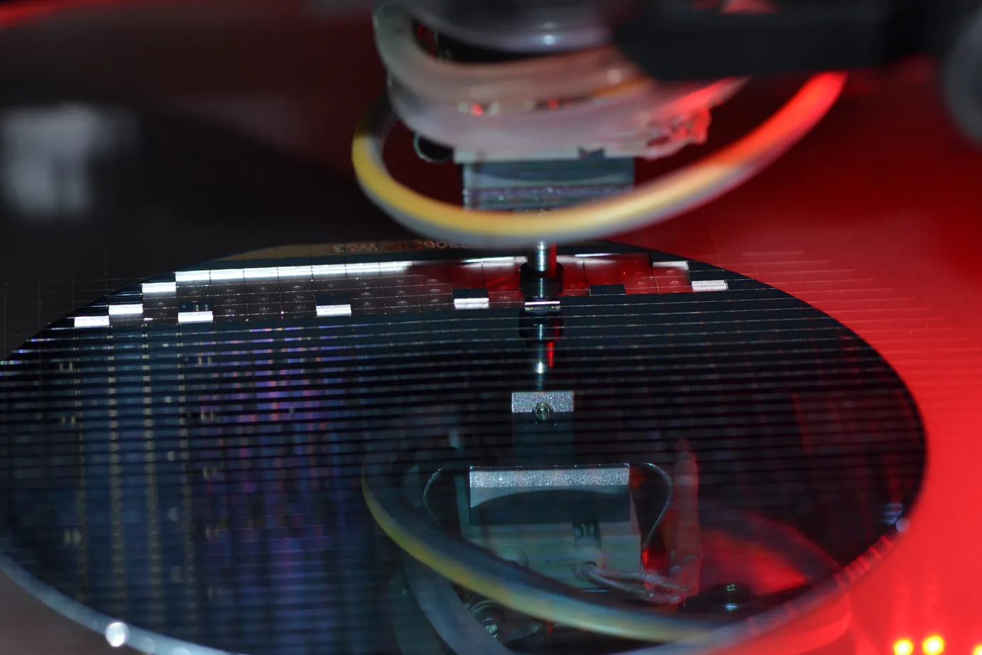 Die bonder pick-and-place head over a wafer under red alignment light
