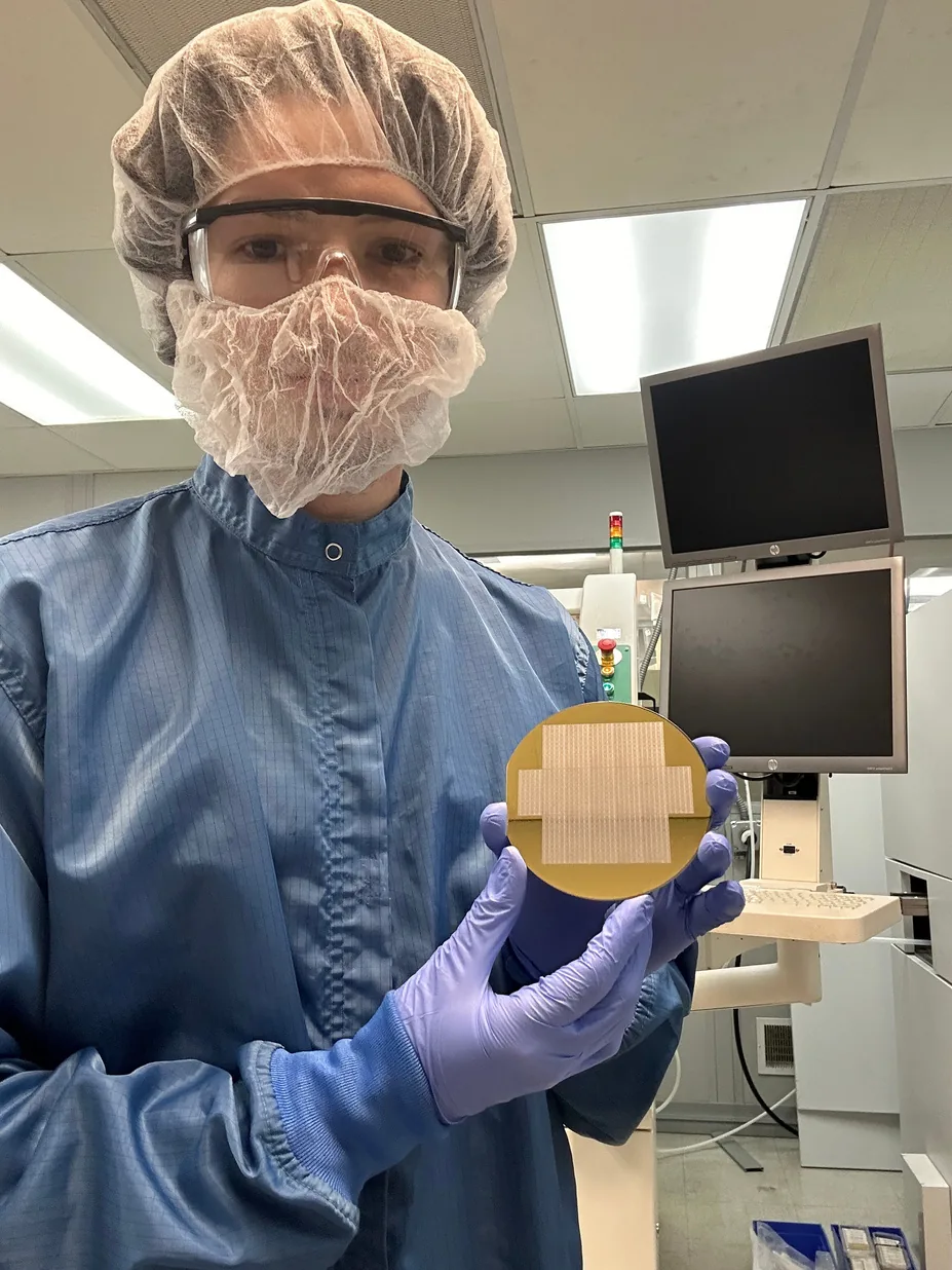 Cleanroom operator in protective garments holding a patterned wafer