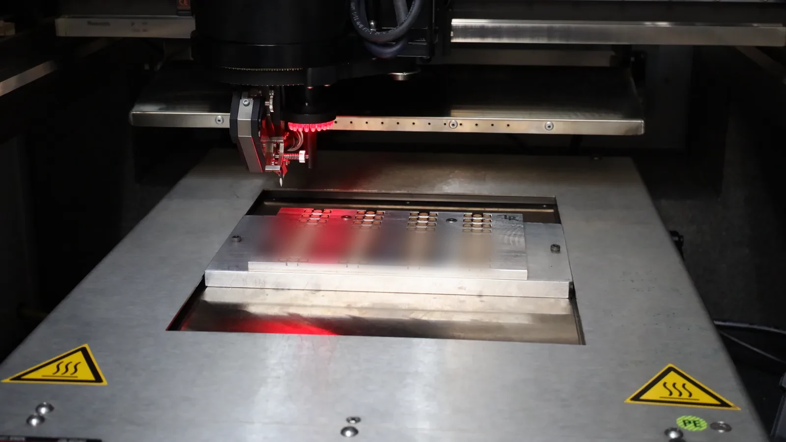 Red-lit bonder over a panel of parts